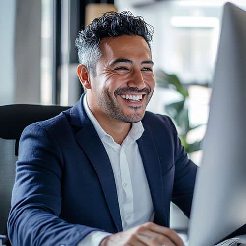 Happy businessman smiling at something on his computer screen