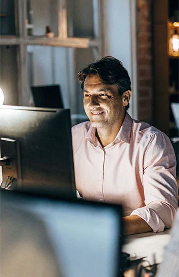 Happy businessman sitting at his computer